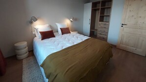 Un dormitorio con cama, lámparas de noche, armario y puerta.