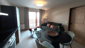 Un espacio habitable compacto con kitchenette, comedor y sofá.
