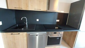 Una cocina moderna con armarios de madera, encimera negra, lavavajillas de acero inoxidable y horno.