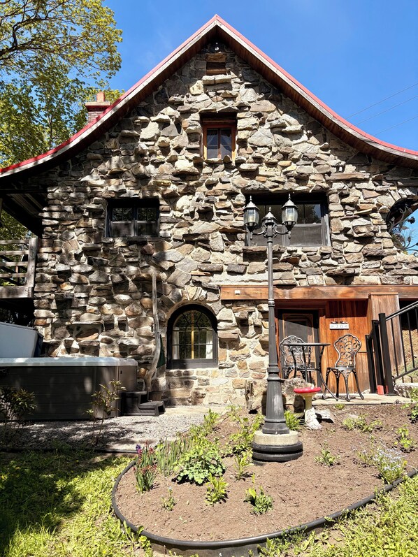 A stone building with a red roof, a wooden door, and a sign with the number 70. - Le Vieil Âtre - Rustic chalet & spa (Saint-Jean-Port-Joli)