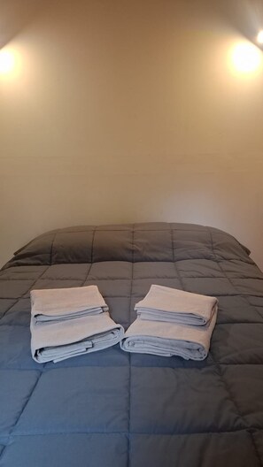 A bed with a dark quilt and two folded towels on it. - Gorgeous 1-bedroom cabin in San Carlos de Bariloche awaits you (San Carlos de Bariloche)