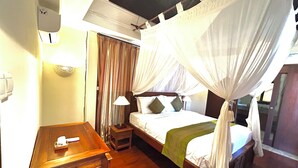 A hotel room with a bed, a nightstand, a table, a lamp, and a curtain. - Patmase Villas in Jimbaran (Badung)