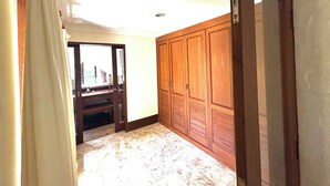 A hallway with a wooden wardrobe, a mirror, and a door leading to another room. - Patmase Villas in Jimbaran (Badung)