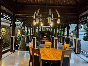 An indoor dining area with a wooden table and chairs, a stone wall, and a hanging light fixture. - Patmase Villas in Jimbaran (Badung)