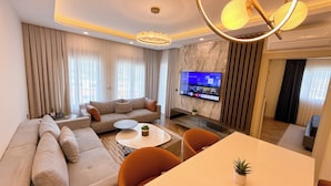 A modern living room with a sofa, a coffee table, and a TV mounted on the wall. - Hiper Suites Residance  (Antalya)