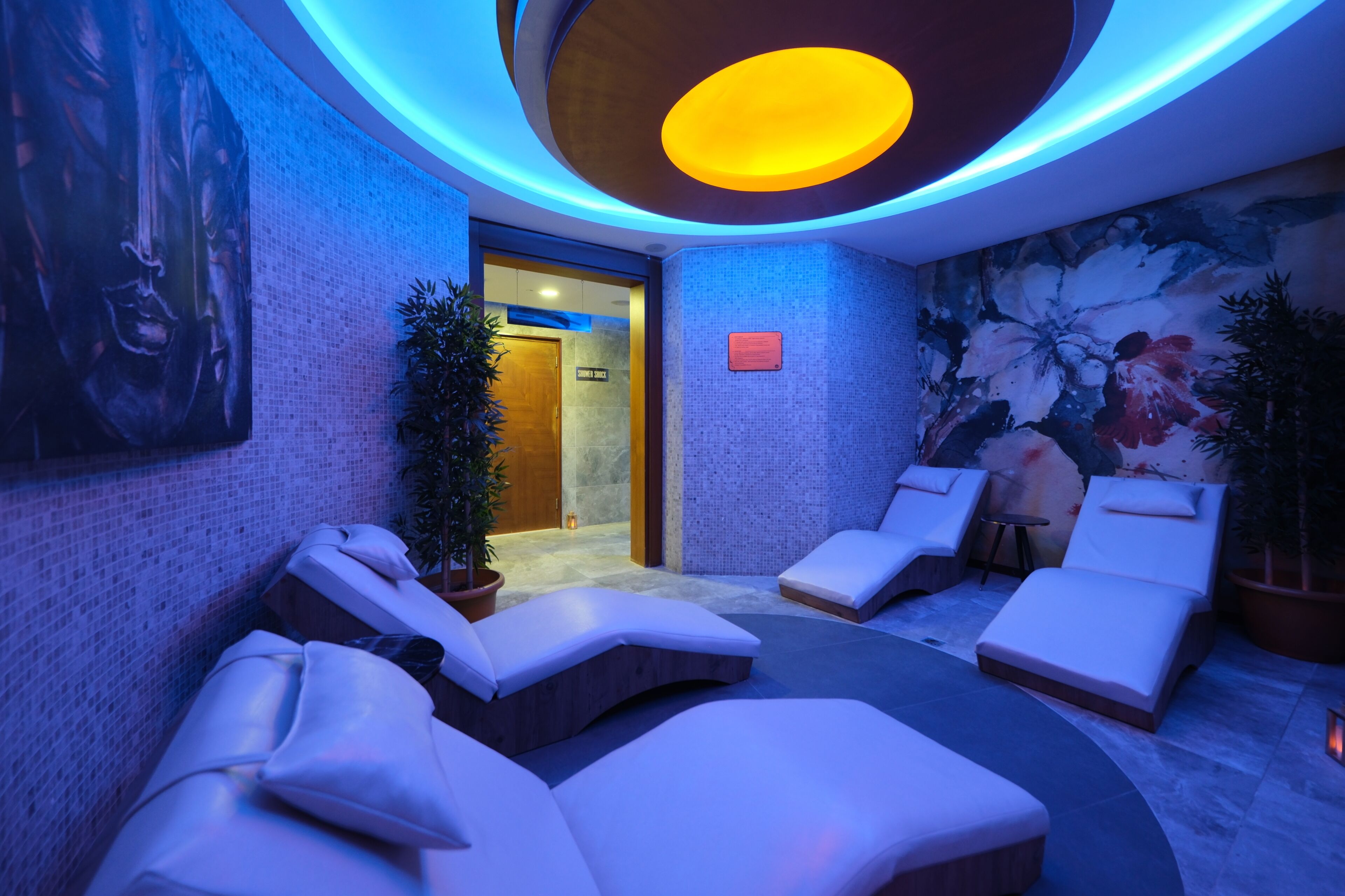 Ein Wellnessbereich mit Massagesesseln, einer Rezeption und einem Wandgemälde.
