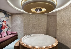 Ein modernes Badezimmer mit einer freistehenden Badewanne, Mosaikwänden und einer Holzbank.