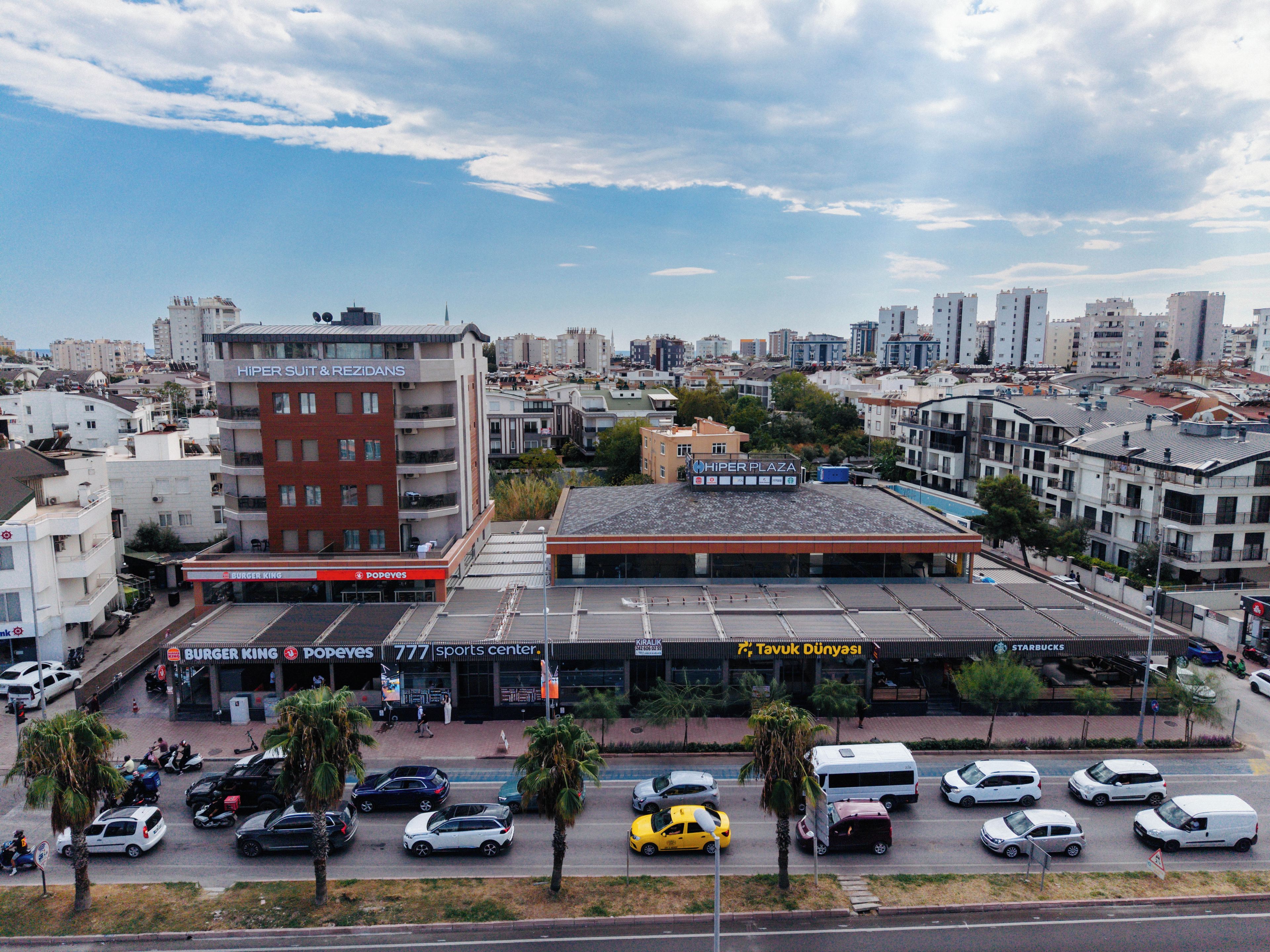 Un edificio a più piani con un centro sportivo e un parcheggio con diversi veicoli.