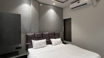 A modern bedroom with a large bed, a ceiling fan, an air conditioning unit, and a flat-screen TV.