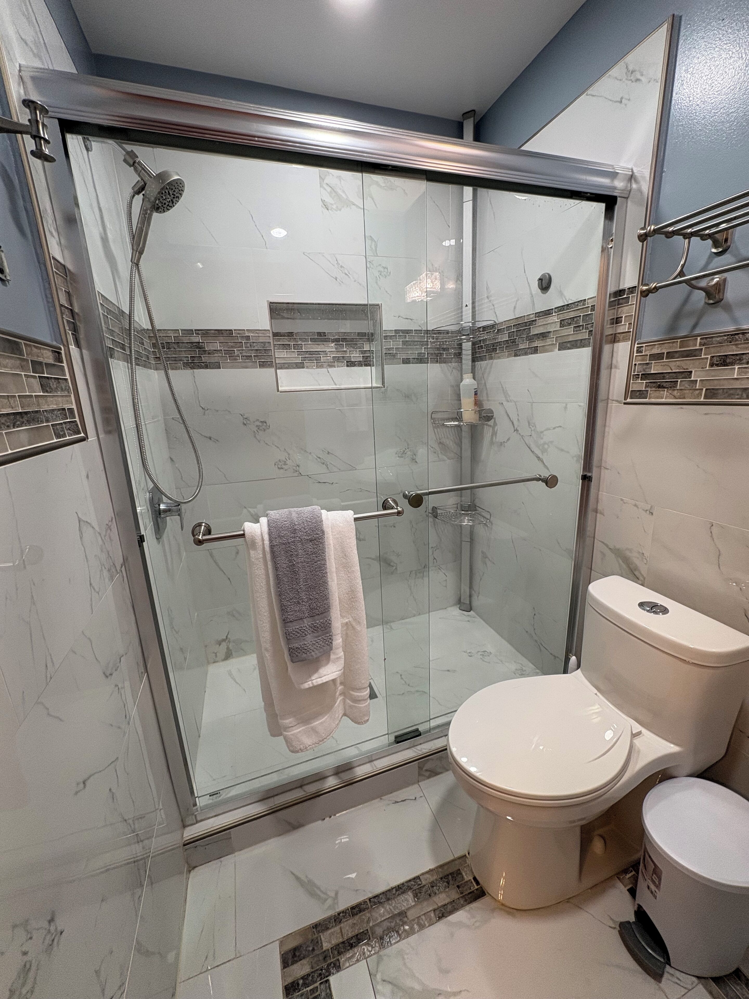 A modern bathroom with a glass-enclosed shower, a toilet, and a sink.