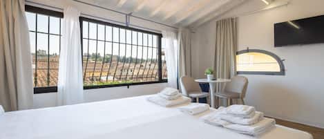 Una habitación de hotel con una cama grande, dos sillas, una mesita y un televisor.