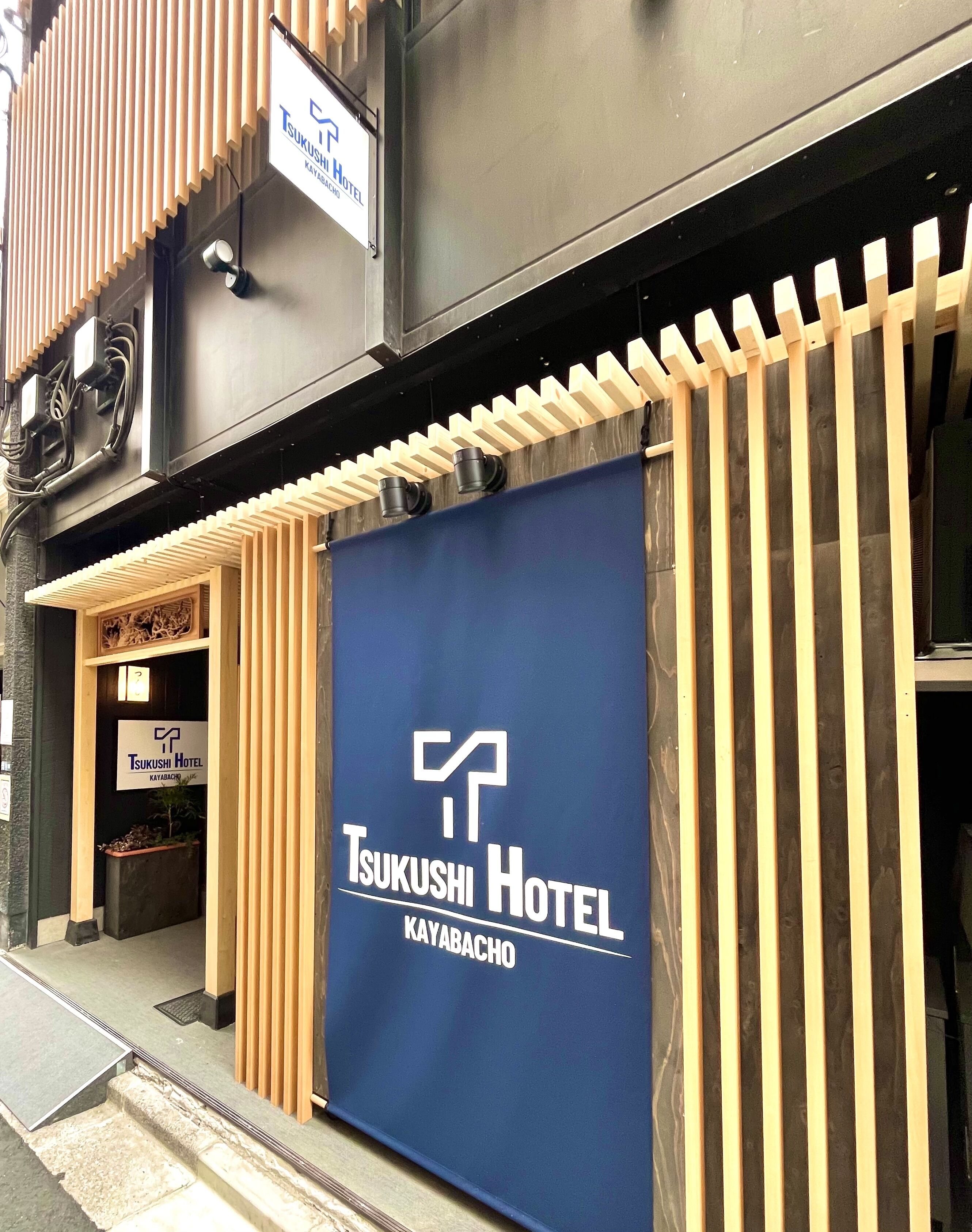 The exterior of Tsukushi Hotel in Kayabacho, featuring a prominent blue banner with the hotel’s logo and name.