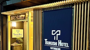 The exterior of Tsukushi Hotel in Kayabacho, featuring a prominent entrance with a sign and a large blue banner displaying the hotel's name. - KAYABACHO TSUKUSHI HOTEL (Tokyo)