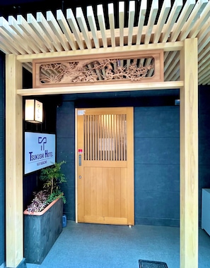 Ein Holzeingang mit einem Schild für das Tsukushi Hotel in Kayabacho.