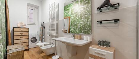 Ein Badezimmer mit Waschbecken, Spiegel, Handtuchhalter und Duschbereich.