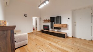 Una sala de estar moderna con piso de madera, un sofá blanco, un televisor y estanterías empotradas.