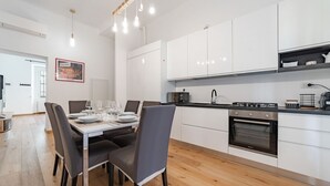 Una cocina moderna con gabinetes blancos, una mesa de comedor con sillas y un horno empotrado.