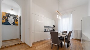 Una cocina moderna con armarios blancos, una mesa de comedor con sillas y un cuadro en la pared.
