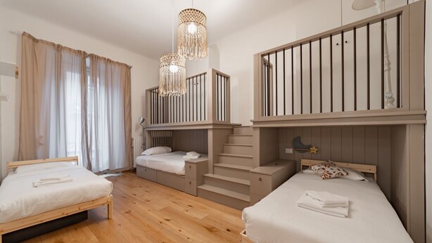 Un dormitorio con dos camas, una escalera y una lámpara colgante.