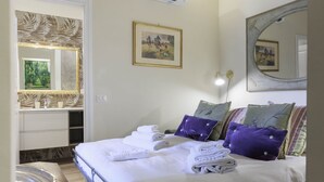 Ein Hotelzimmer mit Bett, großem Spiegel, einem Gemälde und einem Badezimmer mit Waschtisch.