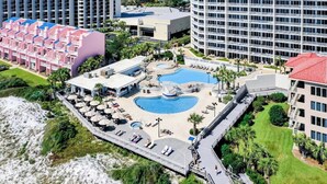 Un resort con diverse piscine, una spiaggia e vari edifici, tra cui un hotel con tetto rosso.