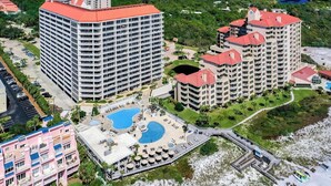 Un hotel moderno con numerosi balconi, una piscina centrale e un'area verde circostante.