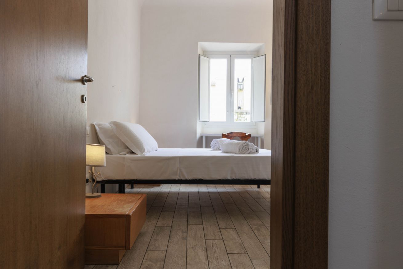 Une chambre à coucher avec un lit, une table de chevet, une fenêtre donnant sur un beau paysage et un plancher en bois.