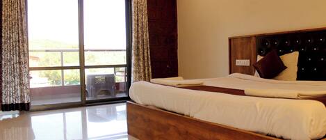 A bedroom with a large bed, a wooden headboard, and a view through a sliding glass door.