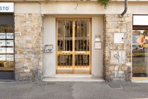 Ein Gebäude mit einer Stein-Fassade, einer Glastür und einem Metallgitter sowie mit an den Wänden befestigten Nummernschildern.