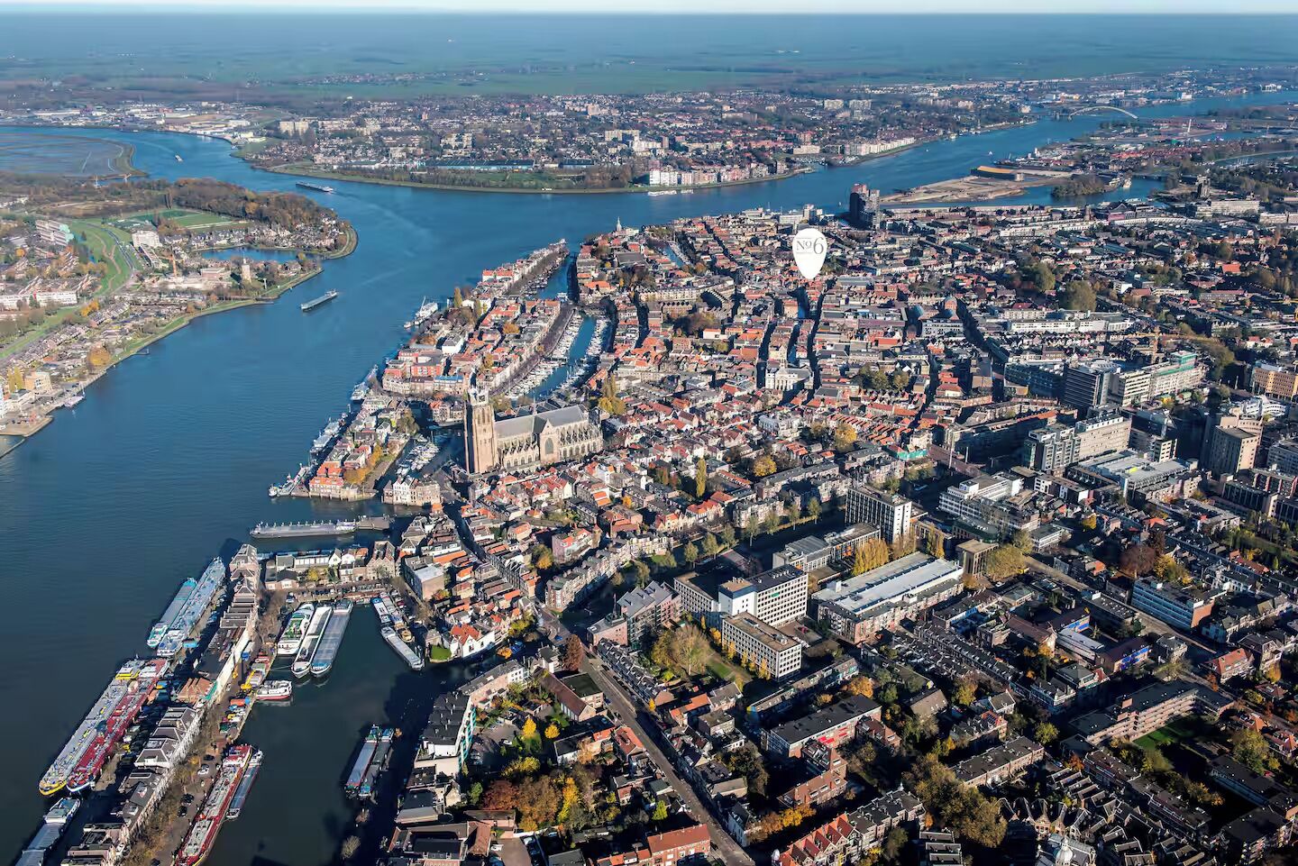 Une vue aérienne d’une ville avec une rivière, une église imposante et une zone urbaine dense comprenant divers bâtiments.