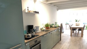 Une cuisine moderne équipée d’un four encastré, d’une machine à café et d’un coin repas avec une table et des chaises.