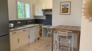 Una cocina moderna con armarios blancos, horno empotrado y una mesa de madera con sillas de metal.