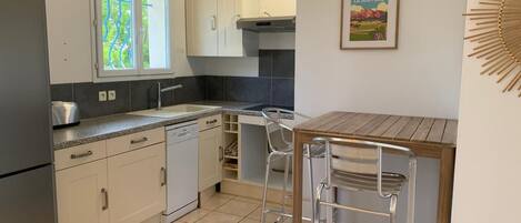 A modern kitchen with white cabinets, a built-in oven, and a wooden dining table with metal chairs.