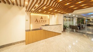 A reception desk with a wooden panel design, a marble floor, and a modern ceiling with wooden slats. - Altuz Apartment Seturan – Private City Studio with Sky Pool Access (Sleman)