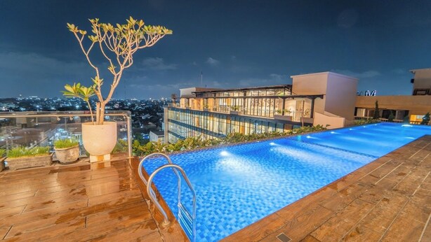 A rooftop pool with a view of the city at night. - Altuz Apartment Seturan – Private City Studio with Sky Pool Access (Sleman)