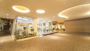 A spacious lobby with a tiled floor, glass partitions, and a motorcycle parked inside. - Altuz Apartment Seturan – Private City Studio with Sky Pool Access (Sleman)