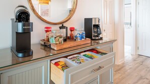Eine moderne Küche mit einer Keurig-Kaffeemaschine, einer Kaffeemaschine und einem Holztablett mit Gewürzgläsern.