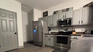 A modern kitchen with stainless steel appliances, grey cabinets, and a wooden floor. - Updated - 3-bedroom house in delightful Sevierville, hot tub, dog friendly (Sevierville)