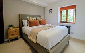 Ein Schlafzimmer mit Bett, Nachttisch, Fenster und Blick sowie Radiator.