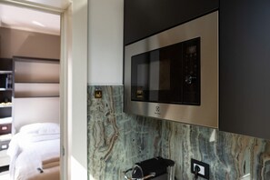 A modern kitchen with a built-in microwave and oven, marble backsplash, and a coffee machine. - Ponte Vecchio Terrace Suite with Jacuzzi (Florence)