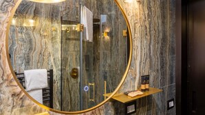 A bathroom with a large mirror, marble walls, a towel rack, and a shelf with toiletries. - Ponte Vecchio Terrace Suite with Jacuzzi (Florence)