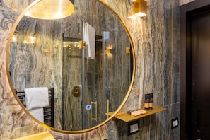 A bathroom with a large mirror, marble walls, a towel rack, and a shelf with toiletries. - Ponte Vecchio Terrace Suite with Jacuzzi (Florence)