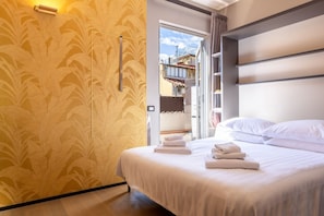 A hotel room with a bed, a door leading outside, and a patterned wall. - Ponte Vecchio Terrace Suite with Jacuzzi (Florence)
