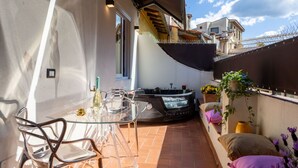 A patio with a glass table and chairs, a hot tub, and a small seating area with cushions. - Ponte Vecchio Terrace Suite with Jacuzzi (Florence)