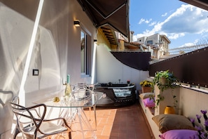 A patio with a glass table and chairs, a hot tub, and a small seating area with cushions. - Ponte Vecchio Terrace Suite with Jacuzzi (Florence)