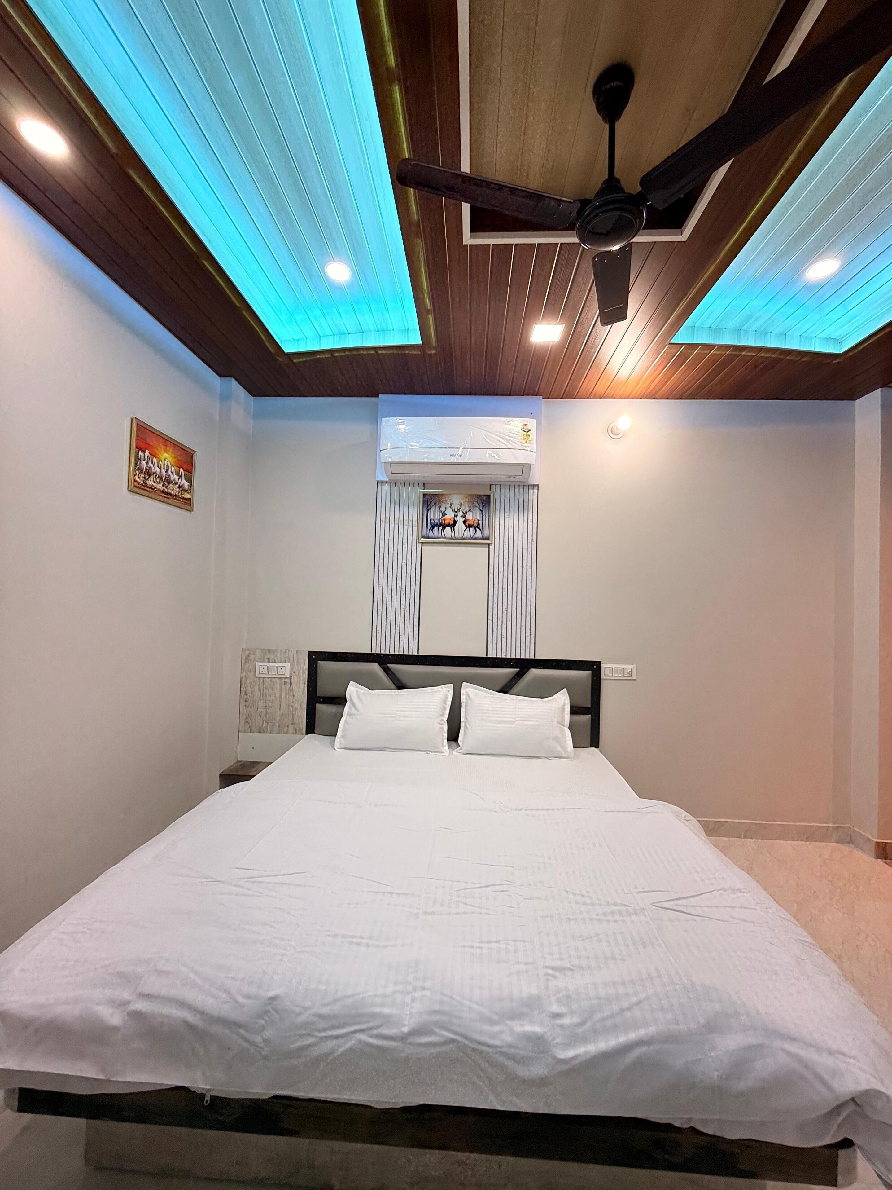 Ein Schlafzimmer mit einem Bett, einem Deckenventilator, eingelassener Beleuchtung, einer Klimaanlage und einem gerahmten Bild an der Wand.