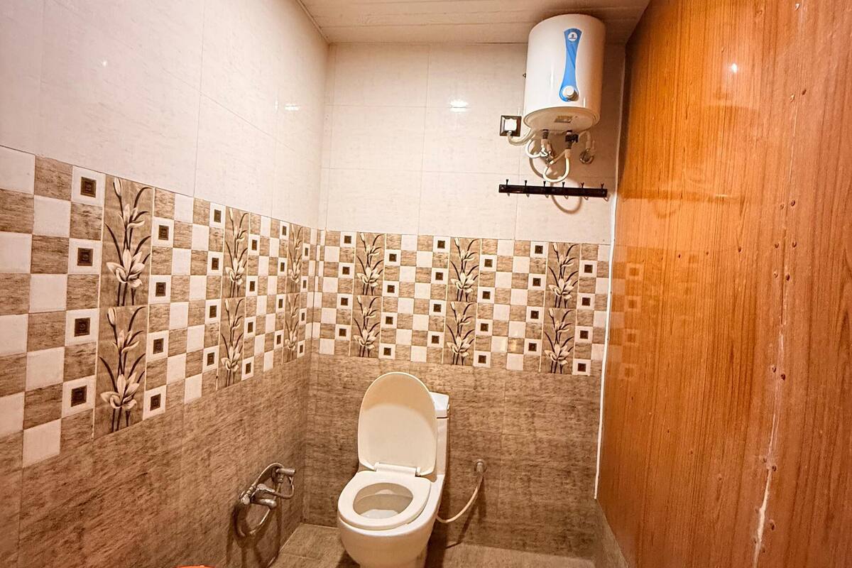 A bathroom with a toilet, a hand dryer, and a water heater mounted on the wall.