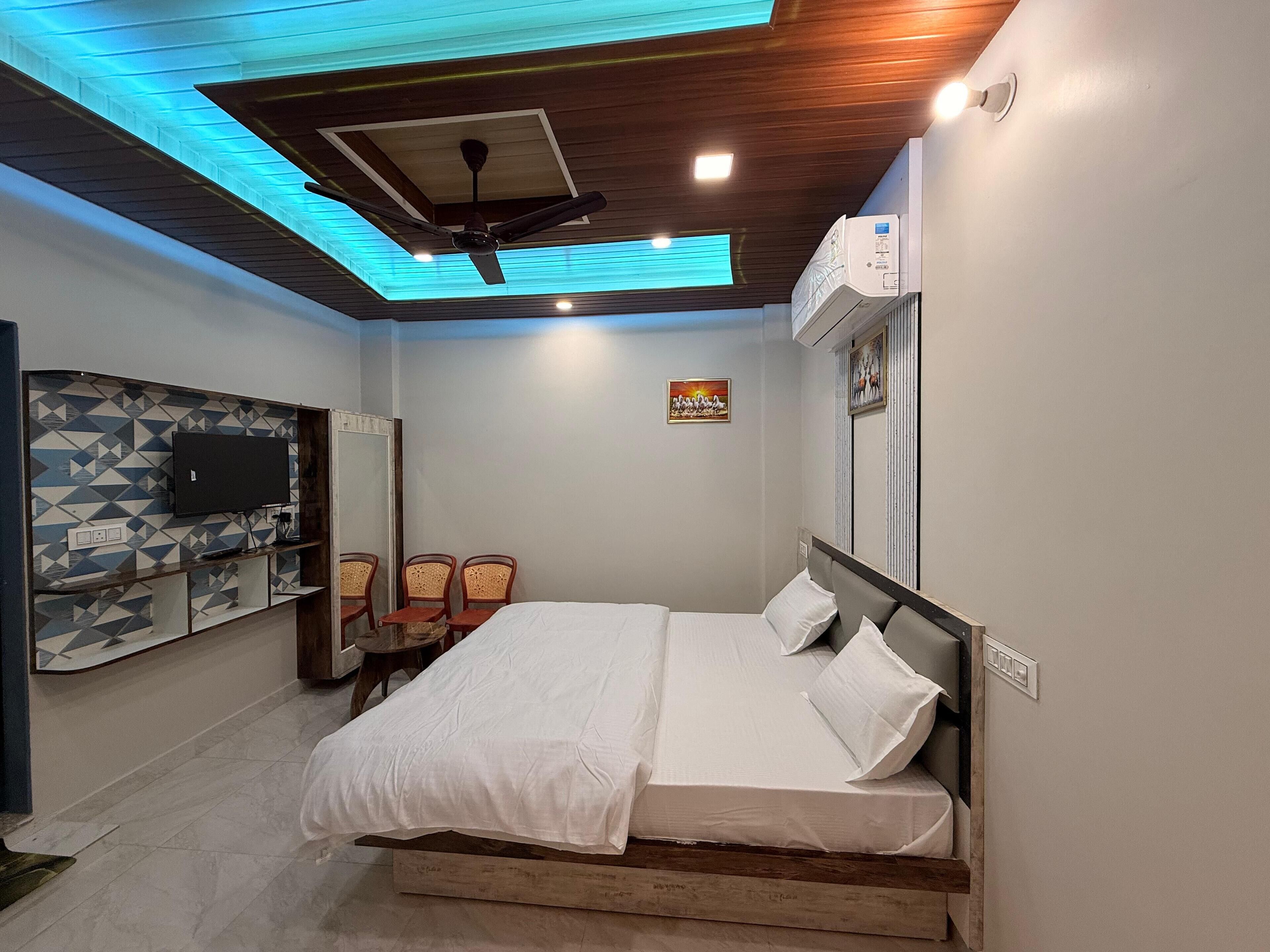 Un dormitorio con cama, ventilador de techo, televisor montado y aire acondicionado de pared.