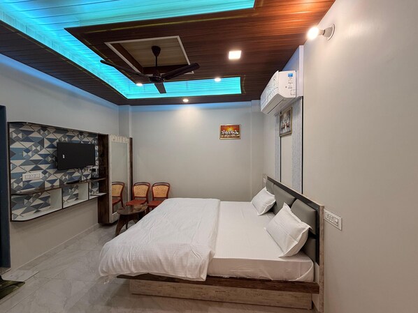 Quarto com cama, ventoinha no teto, televisão montada e ar-condicionado fixado na parede.