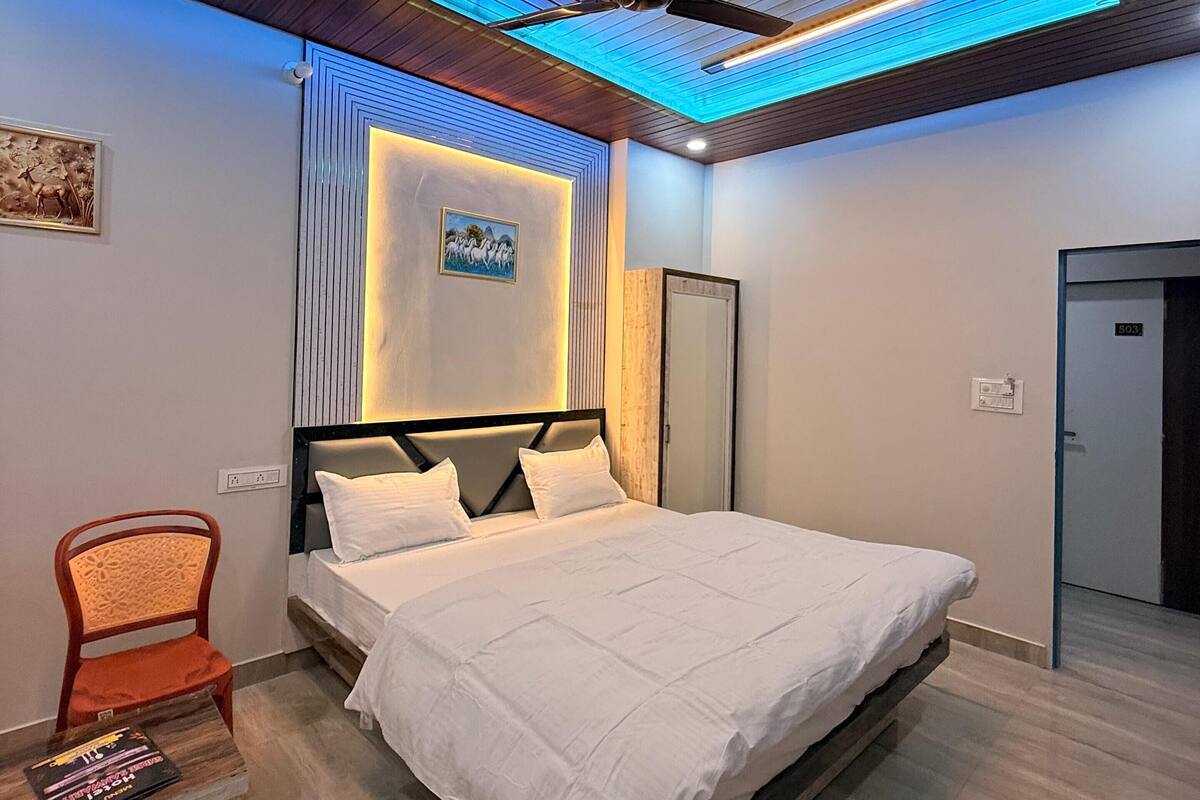 A modern bedroom with a bed, a chair, a ceiling fan, and a door.